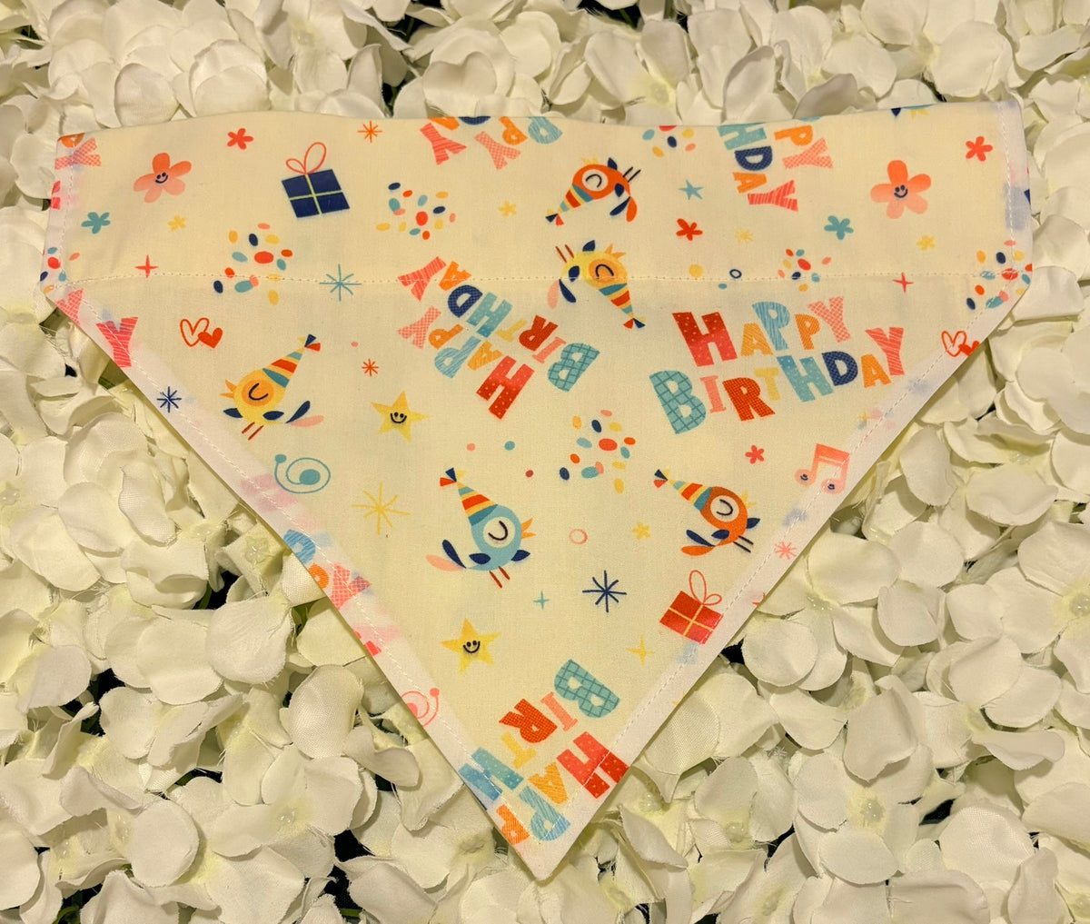 Happy Birthday print dog bandana with party hats, presents and confetti on cream