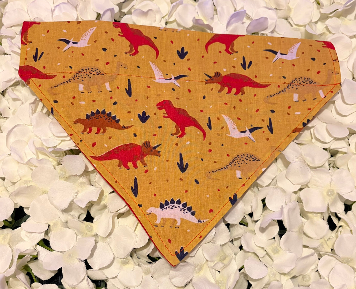 Mustard dog bandana with red and cream dinosaur print on white petals